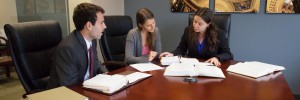 Woman discusses waiver of premium benefits with two attorneys in a conference room.