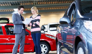 Auto salesman helping a customer with information on a car shes is interested in